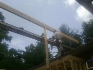 Carpenter setting a ridge beam over a new addition frame — Ice Dam Removal by Roofing Brothers in Cherry Point