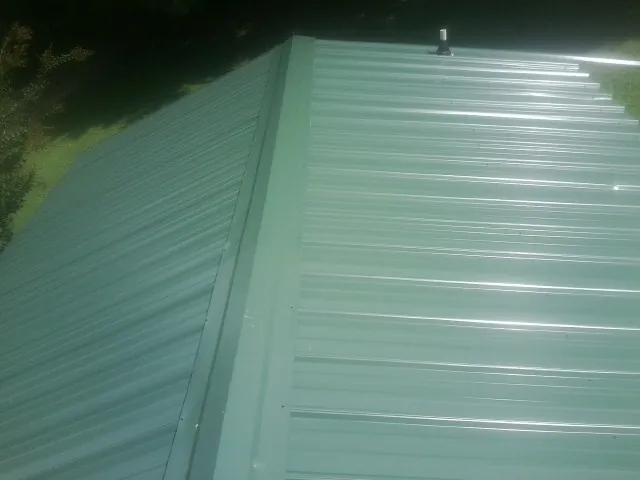 New green metal panels meeting at the ridge of a roof — Flat Roof Repair work by our crew in Cherry Point