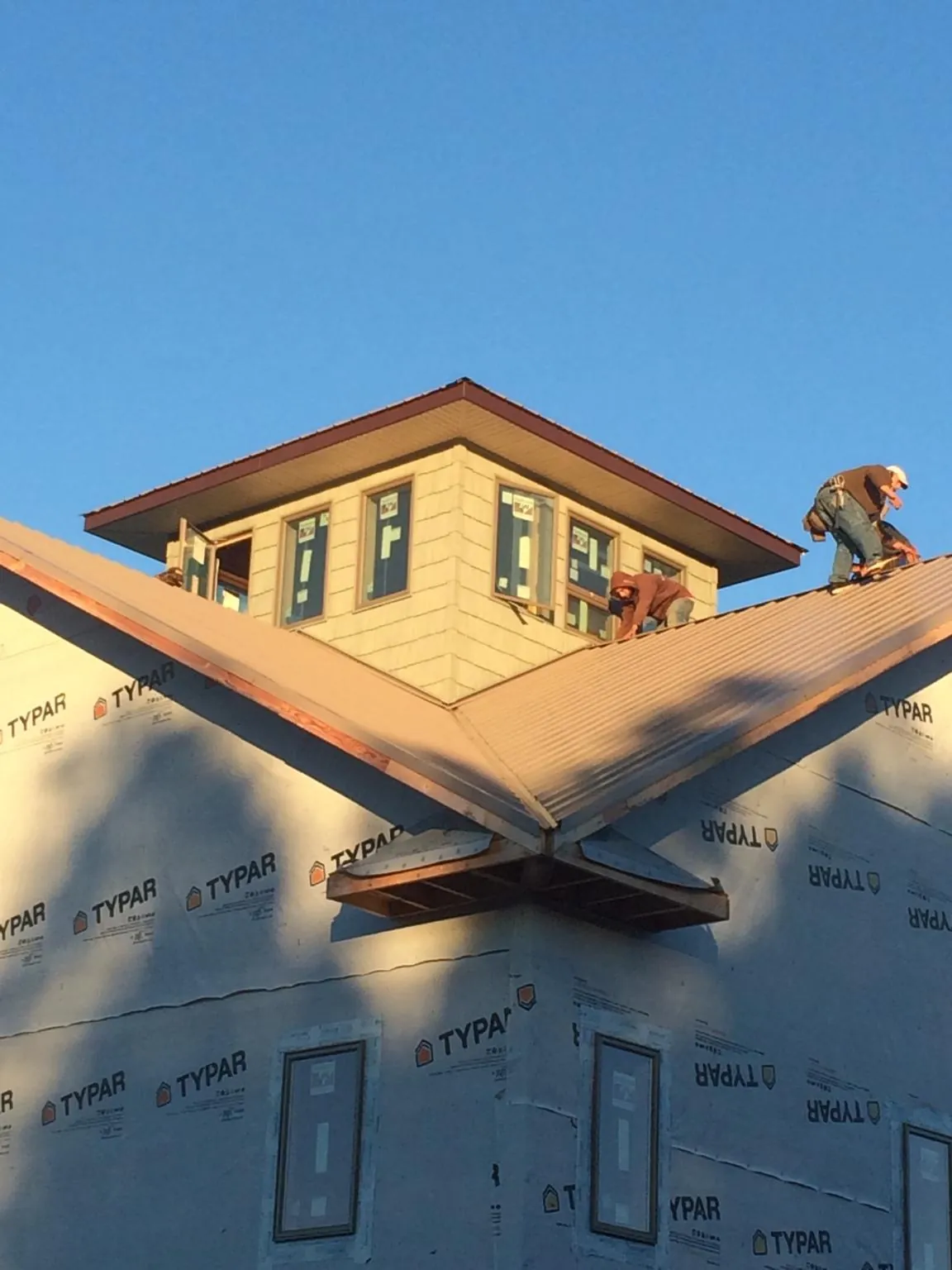 Roofers working around a rooftop cupola on a new metal roof at sunset — Roof Waterproofing in Cherry Point by Roofing Brothers